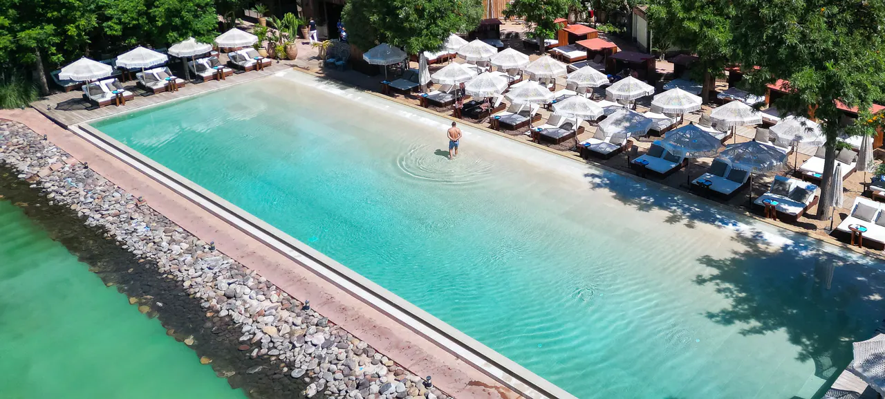 La piscine du Beach Mama vue du ciel, ses beds, ses parasols et la végétation